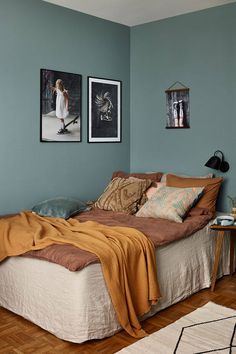 a bed sitting in a bedroom next to two pictures hanging on the wall above it