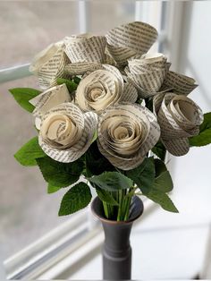 a vase filled with paper flowers on top of a window sill