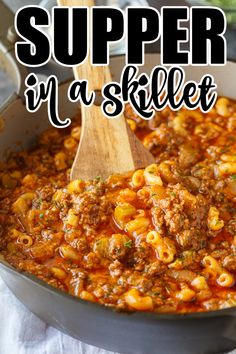 a skillet filled with macaroni and cheese, topped with a wooden spoon