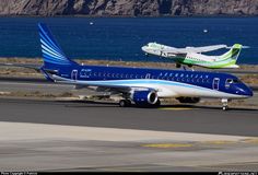 two airplanes are parked on the runway by the water and mountains in the background,