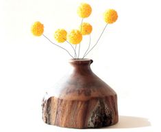 some yellow flowers are in a wooden vase