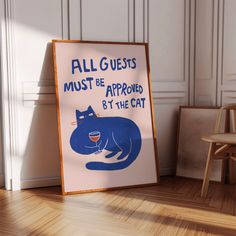 a blue cat sitting on top of a wooden floor next to a sign that says, all guests must be approved by the cat