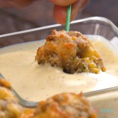 a person is dipping something into a container with some food in it and holding a green straw