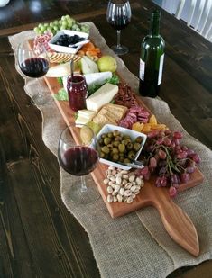 a wooden table topped with lots of food and wine