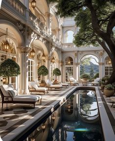 an indoor swimming pool with lounge chairs and potted trees next to it in front of a large building