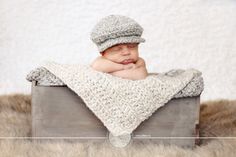 a baby wrapped in a blanket and wearing a knitted hat laying on top of a wooden crate