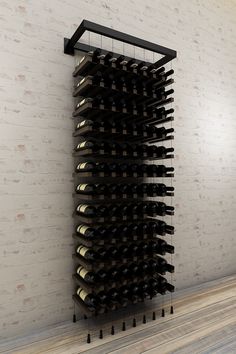 a wine rack with many bottles in it on the floor next to a brick wall