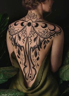 the back of a woman's body is covered in black and white ink with intricate designs