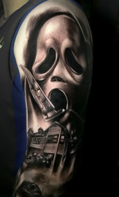 a man's arm with a black and grey tattoo on it, holding a knife