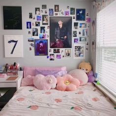 a bed with pink pillows and pictures on the wall above it, along with other stuffed animals