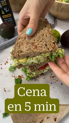 a person holding a sandwich in their hand with the words cena en 5 minn above it