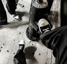 two people standing next to a fire hydrant with their feet on the ground near them