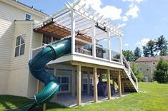 a slide in front of a house with a deck on the second floor and an attached roof