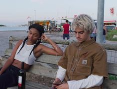 two people sitting on a wooden bench next to each other with headphones in their ears