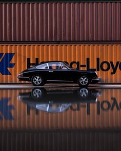 a black car parked in front of a shipping container