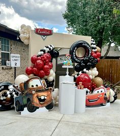 cars and balloons are on display in front of a birthday party at a disney pixar theme park