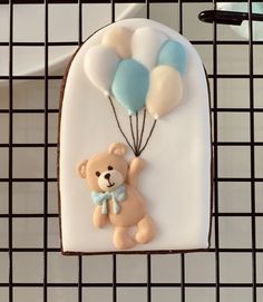 a decorated cookie with a teddy bear holding balloons