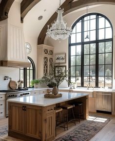 a large kitchen with an island and chandelier hanging from it's ceiling