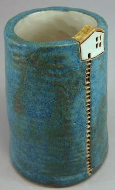 a blue vase with a small house on it's side and a zipper in the middle