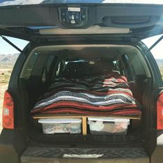 the back end of a vehicle with blankets and other items in the cargo area on it