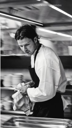 a black and white photo of a man working in a kitchen