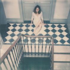 a woman sitting on top of a stair case next to a railing in a room