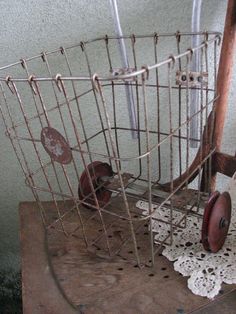 an old fashioned metal basket on a wooden table with lace doily and scissors in it