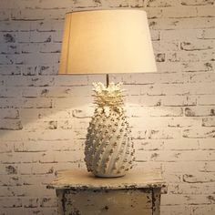 a white lamp sitting on top of a table next to a brick wall