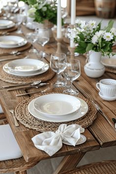 the table is set with white dishes and place settings