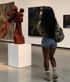 a woman is looking at art on display in an art gallery with her back to the camera