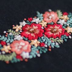 a close up view of some flowers on a black cloth with red, white and green colors