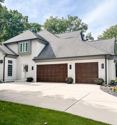 a white house with brown garage doors and windows