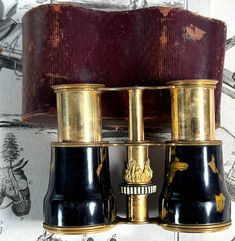 two black and gold binoculars sitting on top of a table