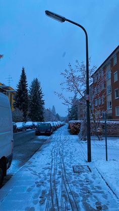 a snowy street with cars parked on the side