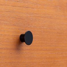 a wooden surface with a black knob on it