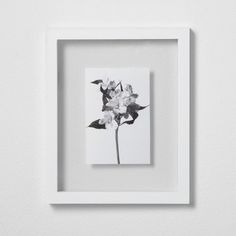 a black and white photo of a flower in a square frame on the wall above it