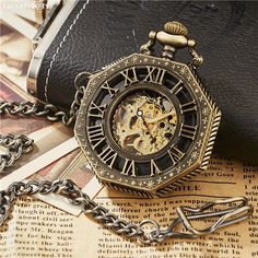 an antique pocket watch sitting on top of a table next to a chain link wallet