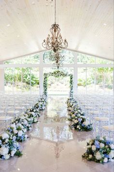 an indoor wedding venue with rows of chairs and chandelier decorated with blue and white flowers