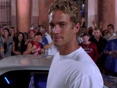 a man standing next to a car in front of a crowd