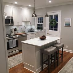 a kitchen with white cabinets and silver appliances