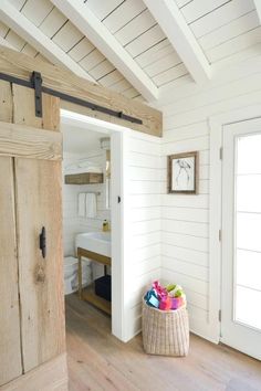 an open door leading to a bathroom with white walls and wood flooring on the side