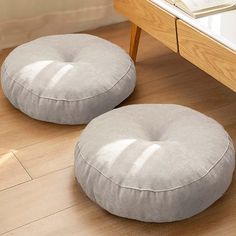 two round pillows sitting on the floor next to a table