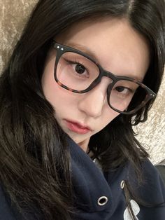 a girl with glasses on her face looking at the camera while wearing a hoodie