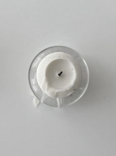 a small white object sitting on top of a table next to a cup filled with liquid