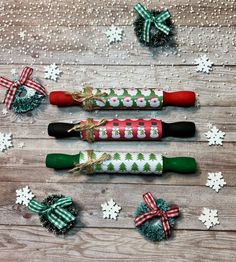 three christmas crackers decorated with bows and snowflakes on a wooden table surrounded by holiday decorations