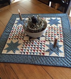 a quilted placemat with candles on it and a potted plant in the center