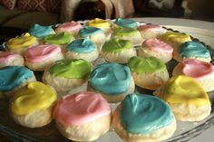 there are many colorful cupcakes on the glass platter and one is frosted with icing