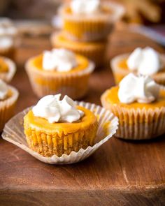 small cupcakes with whipped cream on top are sitting on a wooden table, ready to be eaten