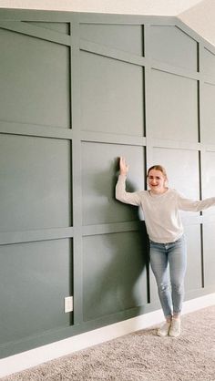 a woman leaning against a wall with her arms out and hands in the air smiling