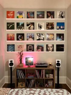 a room with speakers, bookshelves and pictures on the wall